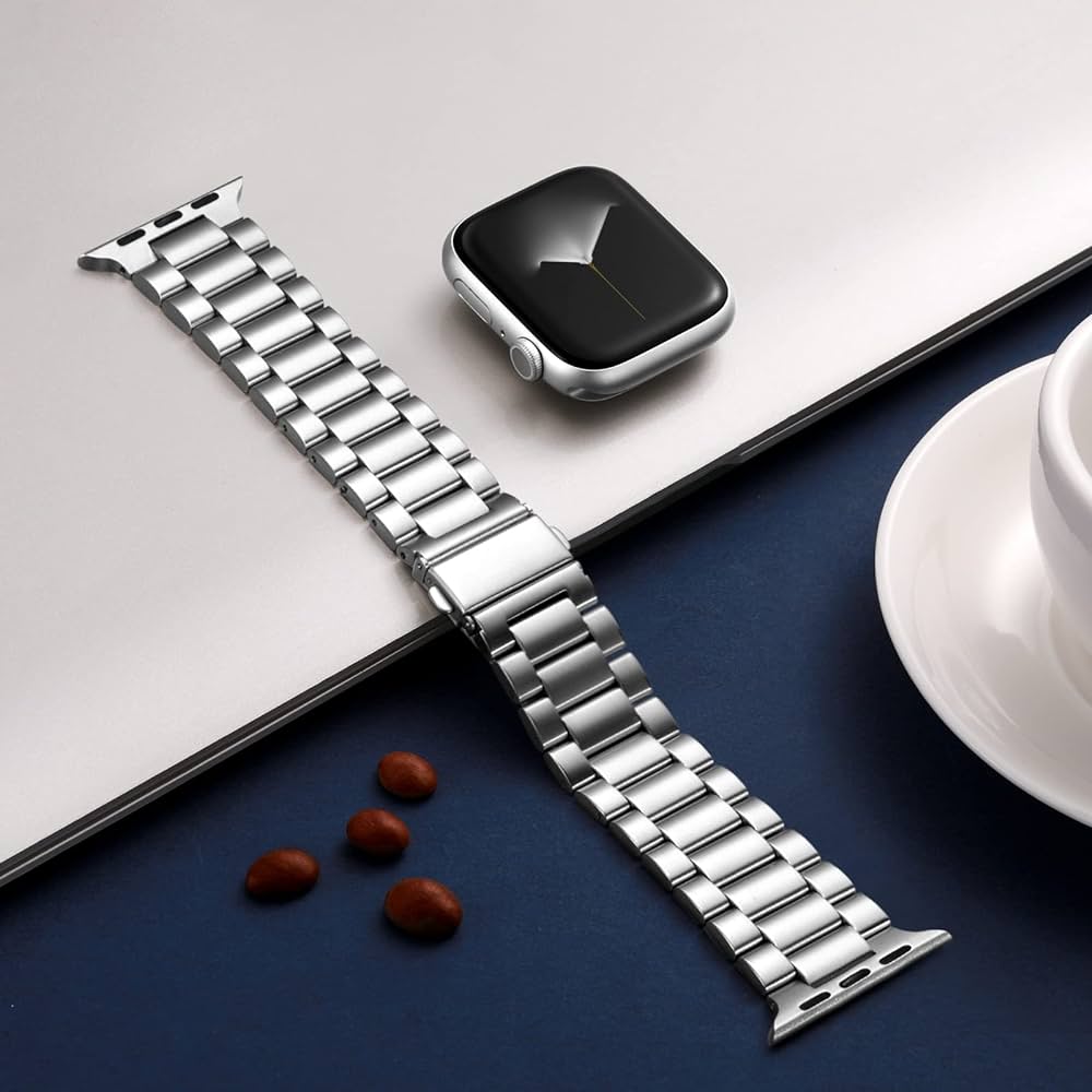 Silver watch strap on a white surface with a smartphone and cup in the background