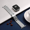 Silver watch strap on a white surface with a smartphone and cup in the background